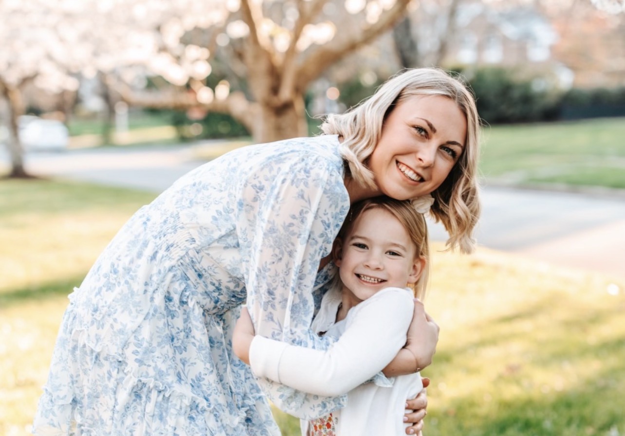 An au pair hugging a host child outdoors
